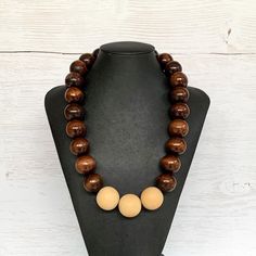 This chunky wood necklace was hand beaded using a mix of large 25mm round dark brown and 28mm round medium tone tan wooden beads in a modern color block design. The necklace measures 24 inches long and is securely fastened with a silver clasp.  Perfect for any gender!  Length can be adjusted if needed - just ask! Wood represents a sense of earthiness, spirituality, creativity, liberty, prosperity, health, and natural touch.  Perfect for meditation, prayer, yoga practices, and everyday wear!    C Brown Wooden Beads Round Jewelry, Brown Wooden Beads Jewelry, Handmade Brown Beaded Necklaces, Handmade Brown Round Beaded Necklaces, Brown Round Wooden Beads Jewelry, Brown Beaded Necklace With Large Round Beads, Brown Round Beaded Necklace With Large Beads, Brown Wooden Necklace With Large Beads, Brown Necklaces With Round Wooden Beads