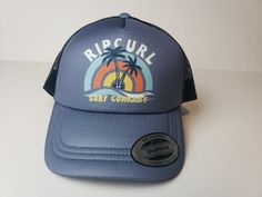 Elevate your beach look with this Rip Curl Sunny Paradise Trucker Hat. The solid blue color complements any outfit, while the mesh back keeps you cool during hot summer days. This one-size-fits-all hat features a vintage-inspired "RIP CURL" brand logo and is perfect for casual occasions. Ideal for men, this hat is a must-have accessory for any beach lover. It's handmade with high-quality materials and includes features such as a mesh back and a comfortable fit. Whether you're heading out for a surf session or just lounging on the beach, this Rip Curl hat is the perfect addition to your outfit. Summer Sports Hat With Mesh Back, Blue Summer Trucker Hat, Blue Adjustable Summer Trucker Hat, Blue Adjustable Trucker Hat For Summer, Summer Blue Snapback Trucker Hat, Blue Snapback Trucker Hat For Summer, Blue Trucker Hat For Vacation, Lightweight Summer Trucker Cap, Lightweight Summer Trucker Hat