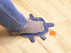 a person standing on top of a wooden floor next to a blue turtle shaped rug