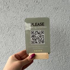 a person holding up a piece of wood with a qr code on it