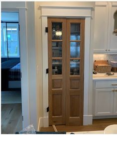 a kitchen with white cabinets and wooden doors in the center is an open pantry area