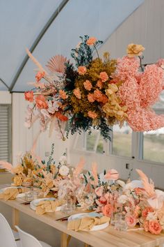 the table is set with flowers and place settings for guests to sit down at it