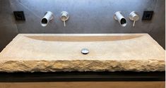 a stone sink with two faucets on the wall