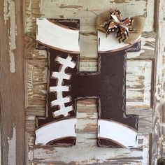 the letter h is made out of wood and has footballs painted on it, along with a burlap bow