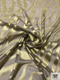 an image of a gold and silver fabric with wavy lines on the top, as if it was made out of silk