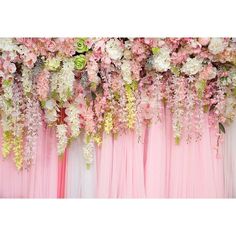 pink and white flowers are hanging on the wall behind a photo booth with black stands