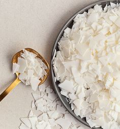 a metal bowl filled with white sugar next to a spoon