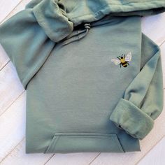 Really soft and comfortable unisex embroidered hoodie with a cute bee embroidered on it made of high quality! Classic fit, 50/50 cotton/polyester. Each hoodie is made in the size and color of your choice, with a unique design. I suggest you use your usual size for a better fit or choose a size for a looser fit.   Hoodies in unisex style with unique design the perfect gift for your best friend, loved one or your new favorite crewneck hooded sweatshirt for autumn, winter, spring and even cool summ Green Casual Hoodie With Custom Embroidery, Casual Green Hoodie With Custom Embroidery, Embroidered Fleece Hoodie, Embroidered Cotton Hoodie, Green Hooded Hoodie With Letter Embroidery, Green Hooded Sweatshirt With Custom Embroidery, Green Hoodie With Letter Embroidery, Embroidered Fleece Hooded Sweatshirt, Green Embroidered Hooded Sweatshirt