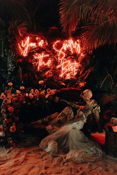 a man and woman sitting in front of a neon sign