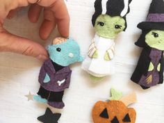 a hand is pointing at small felt halloween decorations