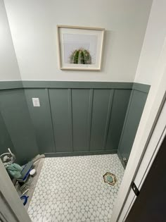 a bathroom with green walls and white tile flooring is seen from the door way