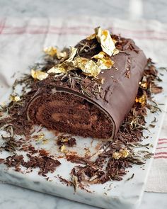 a piece of chocolate cake sitting on top of a white marble slab covered in gold leaf