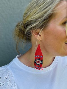 Be inspired by the stunning patterns and art of the southwest and Aztec cultures with the Dakota Earrings. Their vibrant design brings a pop of color, texture, and movement to any outfit. A true statement piece that is impossible to ignore, these earrings are the result of a collaboration between our team in East Tennessee and skilled artisans in India, ensuring each pair is uniquely hand-beaded. Details: -gold plated, stainless steel, fish-hook style earring -glass seed beads -Approx. 4.25in dr Southwestern Red Earrings With Colorful Beads, Red Southwestern Style Earrings For Festivals, Southwestern Red Earrings For Festival, Southwestern Style Red Earrings For Festival, Southwestern Red Beaded Dangling Earrings, Southwestern Red Beaded Earrings With Dangling Beads, Southwestern Style Red Earrings With Dangling Beads, Southwestern Red Earrings With Dangling Beads, Southwestern Red Drop Earrings