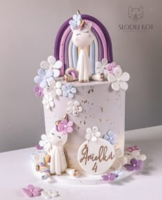 a white cake decorated with flowers and unicorn figurines