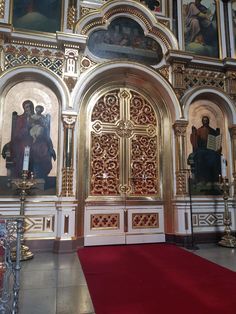 the interior of an ornate church with paintings on the walls and red carpeted floor