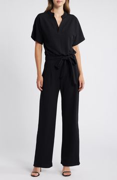 A sash cinches the waist of this comfortable stretch-enriched jumpsuit framed by short sleeves and a collared V-neckline. Mandarin collar V-neck Short sleeves Removable sash 90% polyester, 10% spandex Dry clean Made in the USA Chic Belted Short Sleeve Jumpsuits And Rompers, Chic Belted Jumpsuits And Rompers With Short Sleeves, Chic Belted Jumpsuit With Short Sleeves, Chic Belted Short Sleeve Jumpsuit, Elegant Black Short Sleeve Jumpsuits And Rompers, Short Sleeve Jumpsuit With Tie Waist For Work, Workwear Jumpsuit With Tie Waist And Short Sleeves, Solid Color Tie Waist Jumpsuits For Work, Formal Solid Short Sleeve Jumpsuits And Rompers