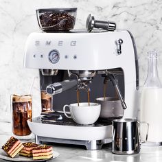 an espresso machine with coffee being poured into it and pastries next to it