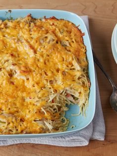 a casserole dish on a blue plate with a fork and spoon next to it