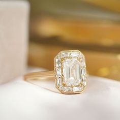 Item Details: One lab created emerald-cut center diamond weighing approx. 1.50 ctw, D or E color VS clarity, GIA certified. Thirty-eight natural round brilliant and french cut baguette diamonds weighing approx. 0.82 ctw, F color VS clarity. This ring can be made in two styles. "In line" which means the mosaic portion of the ring sits flush with the finger, and "Raised" which means the mosaic portion is elevated slightly leaving room for a wedding band to nest with it. Crafted in your choice of 1 20s Engagement Ring, Vintage Gold Emerald Cut Diamond Ring, Vintage Inspired Engagement Ring, Vintage Emerald Cut Gold Diamond Ring, French Halo Engagement Ring, Vintage Mosaic Engagement Ring, Art Deco 14k Gold Wedding Ring With Diamond Accents, Berlinger Jewelry, Wedding Art Deco Diamond Ring Baguette Cut