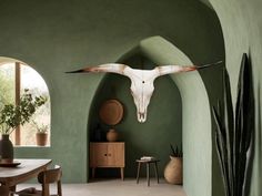 a living room with green walls and a cow skull hanging on the wall above it