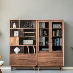 a wooden bookcase sitting next to a white vase on top of a hard wood floor