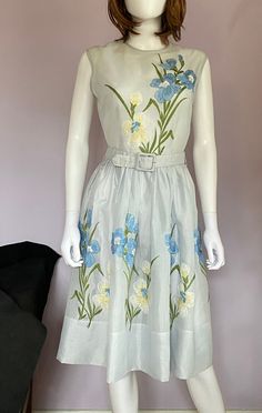 "Simple but elegant, this vintage sleeveless dress is perfect for any summer occasion.  It is made from a sheer polyester and  lavishly embroidered with blue and yellow flowers.  The waist measures 28\" but can be cinched tighter with the matching belt.  Bust measurement is 36\"; skirt length is 25\"; it's 16\" across the shoulders.  Metal zipper in the back.   Gently worn years ago and carefully stored." Summer A-line Sleeveless Dress With Floral Embroidery, Summer Sleeveless A-line Dress With Floral Embroidery, Sleeveless Floral Applique Dress For Summer, Sleeveless Floral Applique Summer Dress, Fitted Sleeveless Dress With Floral Applique For Summer, Vintage Sleeveless Floral Dress For Spring, Sleeveless Floral Embroidery Dress For Summer Garden Party, Spring Party Sleeveless Dress With Floral Embroidery, Fitted Vintage Sleeveless Dress For Spring