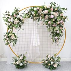 an arrangement of flowers is arranged on a circular backdrop with greenery in the center