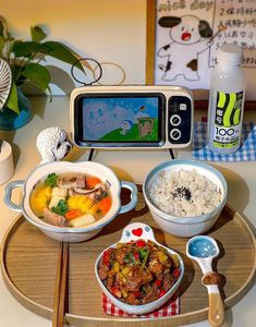 a tray with rice, meat and vegetables in front of a digital camera on top of it