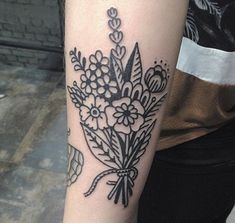 a woman's arm with a bouquet of flowers tattooed on the left side of her arm