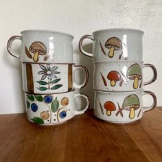 four coffee mugs are stacked on top of each other with mushrooms painted on them