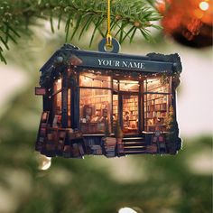 an ornament hanging from a christmas tree with a book store in the window