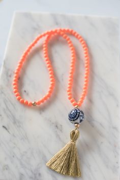 A ginger jar-inspired porcelain bead is accented by orange resin beads and a white tassel. Tassel measures 3.5" and necklace measures 32" long. Handmade in Charleston, South Carolina. Orange Resin, Hand Painted Beads, White Tassel, Tassel Jewelry, Ginger Jar, Charleston South Carolina, Sans Souci, Resin Beads, Ginger Jars