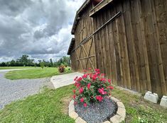 a flower pot sitting in the middle of a graveled area next to a barn