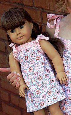 the doll is wearing a pink dress with flowers on it, and pointing to her right