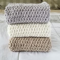 three crocheted blankets stacked on top of each other in front of a bed