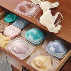 an open drawer filled with lots of different colored dishes on top of a wooden table