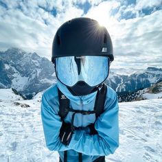 a person wearing a helmet and goggles standing on top of a snow covered slope