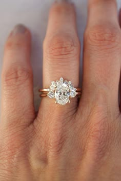 a woman's hand with a diamond ring on top of her finger and an engagement band