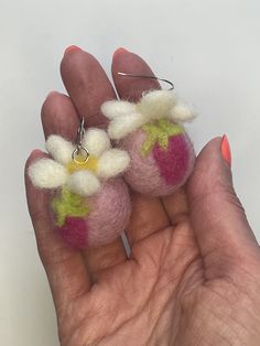 a hand holding two small felted flowers