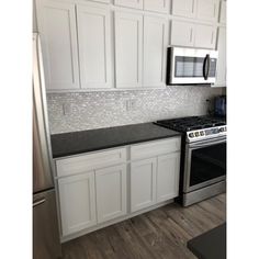 a kitchen with white cabinets and stainless steel appliances