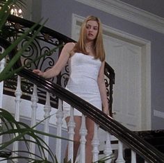 a woman in a white dress is standing on the stairs with her hands behind her back