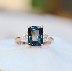 a blue and white diamond ring sitting on top of a piece of wood