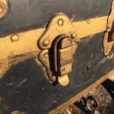 an old black and yellow suitcase with metal latches on the front, sitting outside