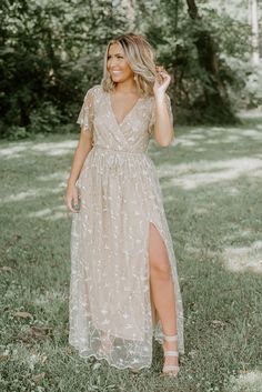 a woman standing in the grass wearing a dress with an open front and side slit