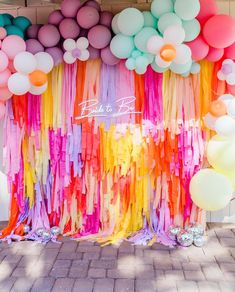 a bunch of balloons and streamers hanging from the ceiling