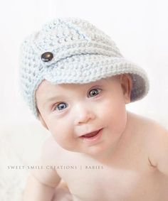 a baby is wearing a crocheted hat and smiling