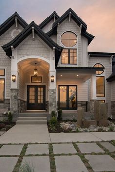 a large house with two story windows and stone walkway leading up to the front door