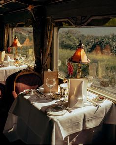 there is a table set for two in the dining car on the train with a view out the window