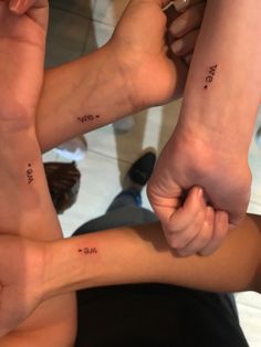 three people holding hands with small tattoos on them