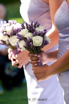 two bridesmaids holding bouquets of white and purple flowers on their wedding day